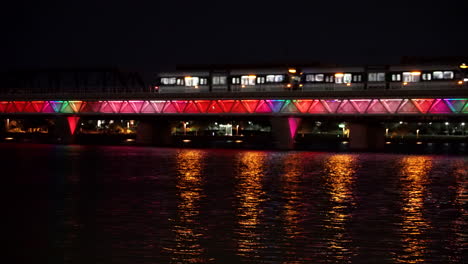 tram over water bridge at night with colorful lights