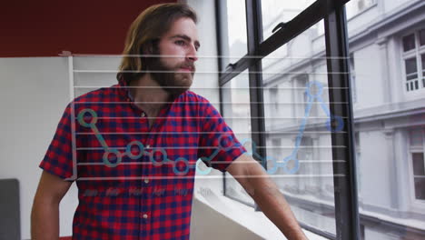 Animación-De-Nombres-De-Meses-Y-Gráfico-Sobre-Un-Hombre-Caucásico-Mirando-A-Través-De-Una-Ventana-De-Vidrio