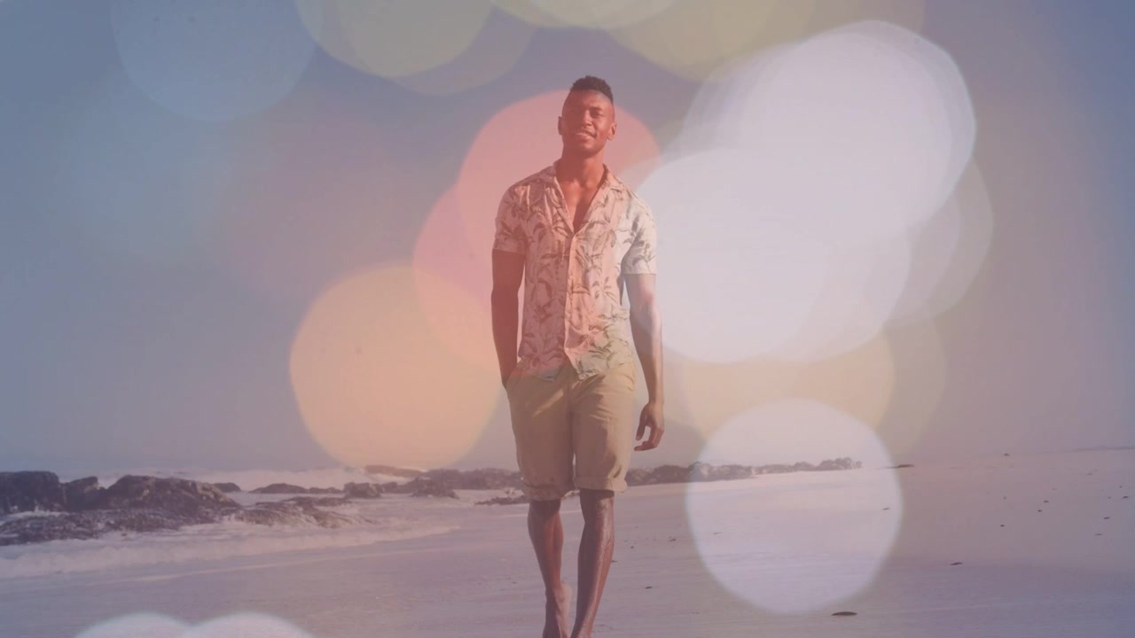 Vertikal video: Mand går fra horisonten mod kameraet på vådt sand, mens et bokeh-overlay afslører marketing.