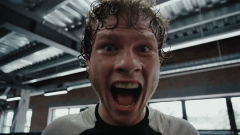 victory fighter screaming in fitness center. sportsman showing power on ring