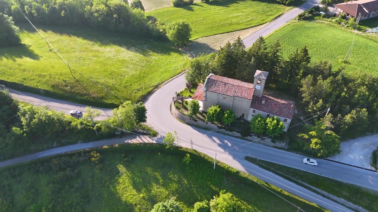 Dronekuvaus tallentaa historiallisen kivikirkon ja mutkittelevia teitä Italian kumpuilevilla kukkuloilla.