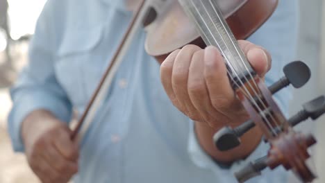 primer plano de las manos de un hombre tocando el violín