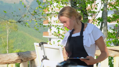 woman painting outdoors with mountain view