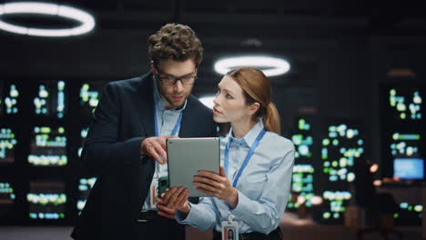 man woman server technicians working pad computer in night data center closeup