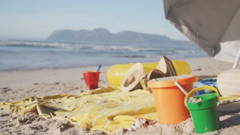 vista de paraguas, cubos de san, sombreros y mantas en la playa