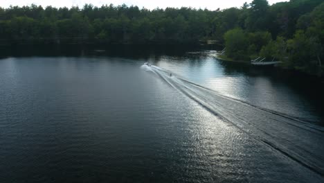 a skier being towed behind a powerboat while participating in the fast-paced activity of water skiing, which involves skimming the surface of the water with one or more skis