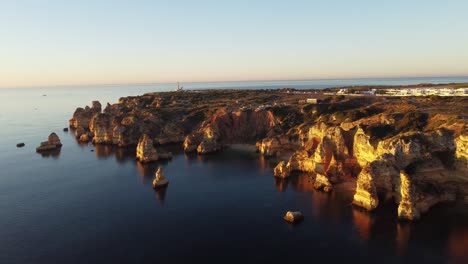 4K-Praia-do-Camilo-at-sunrise-with-brightly-coloured,-blue-sea-water