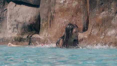 Dame-Ruht-Im-Pool-Mit-Wasserfall-Gegen-Steine-In-Zeitlupe