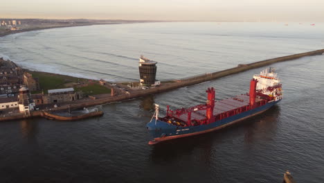 aerial view of a cargo ship entering aberdeen harbour at sunset, aberdeenshire, scotland, uk