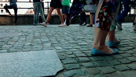 People-walk-on-a-crowded-sidewalk,-close-up-view-of-the-sidewalk-and-legs-to-knee-height,-slow-motion-on-shoes-and-footsteps