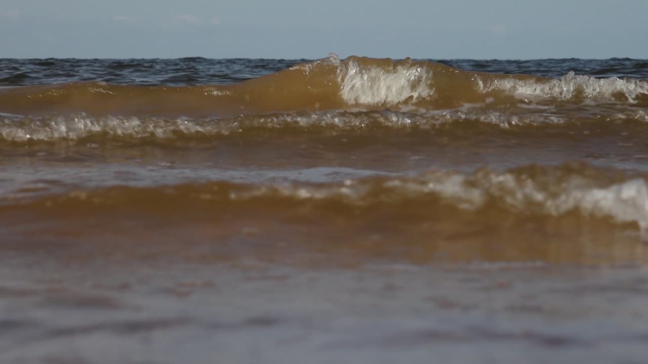 부드러운 바물 물결이 모래 해변을 가로질러 물과 땅 사이에 평화롭고 진정되는 상호 작용을 만니다.