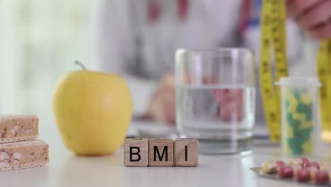 doctor's table with bmi blocks, apple, supplements, and measuring tape for healthy lifestyle and weight management