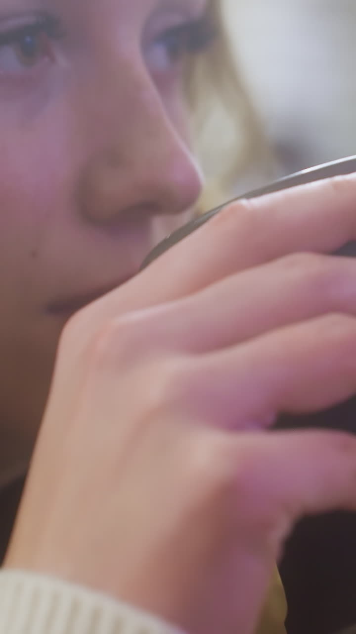 Close-up of female hand in brown shearling jacket gently lifting cup of coffee at cozy cafe table, perfect for capturing moments of relaxation, warmth, and peaceful enjoyment