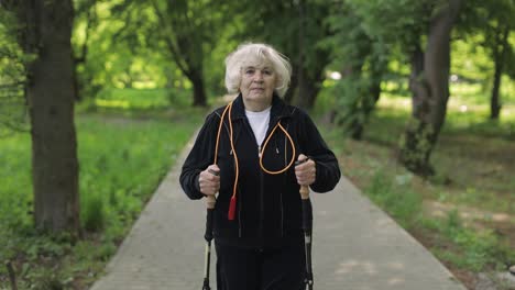 Active-senior-old-woman-training-Nordic-walking-with-ski-trekking-poles-in-park