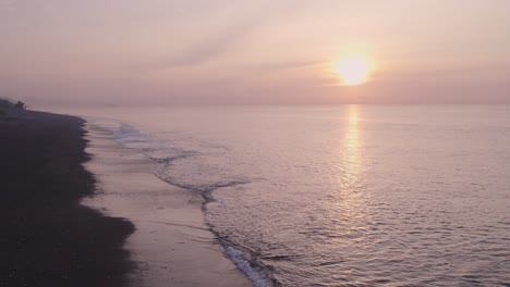 Amazing-sunrise-at-Pantai-Goa-Lawah-with-a-calm-sea-Bali-Indonesia,-aerial