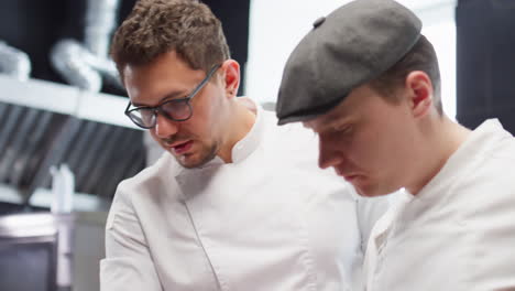 chef teaching assistant how to serve restaurant dishes
