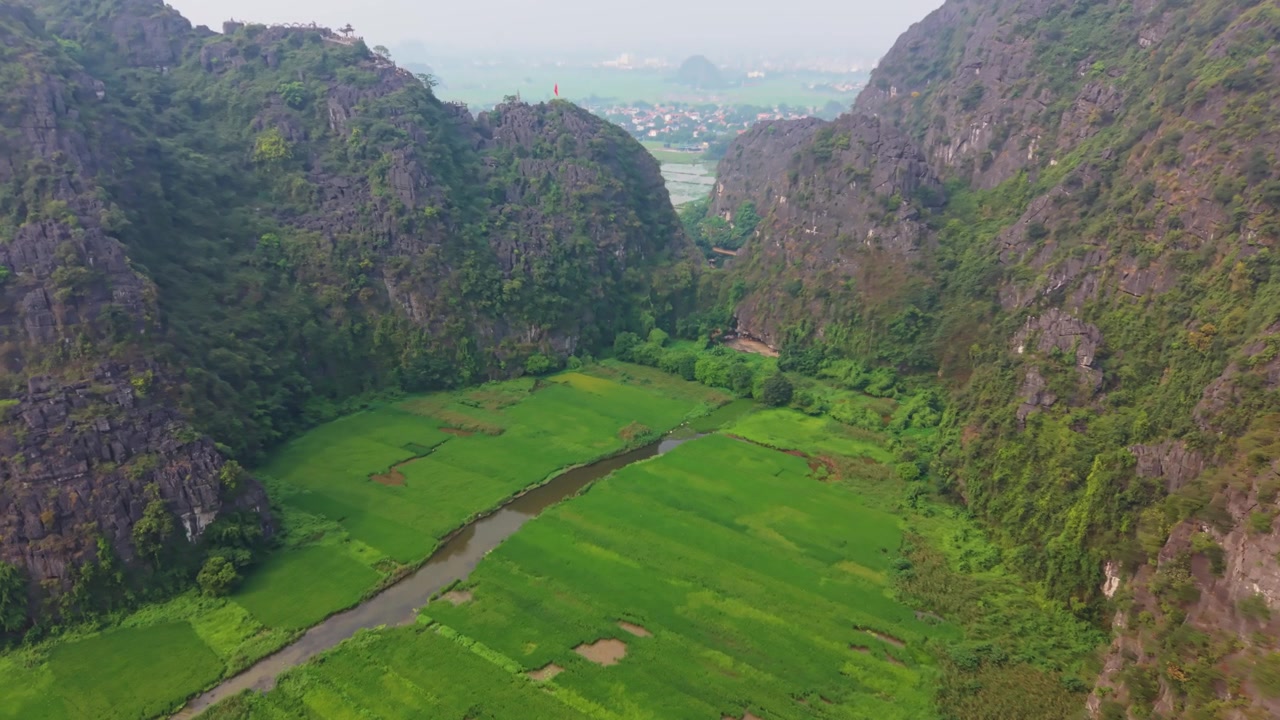 Cảnh quay drone điện ảnh về các khối núi đá vôi karst của Ninh Bình với một dòng sông thơ mộng uốn lượn qua những cánh đồng lúa xanh tươi ở Việt Nam