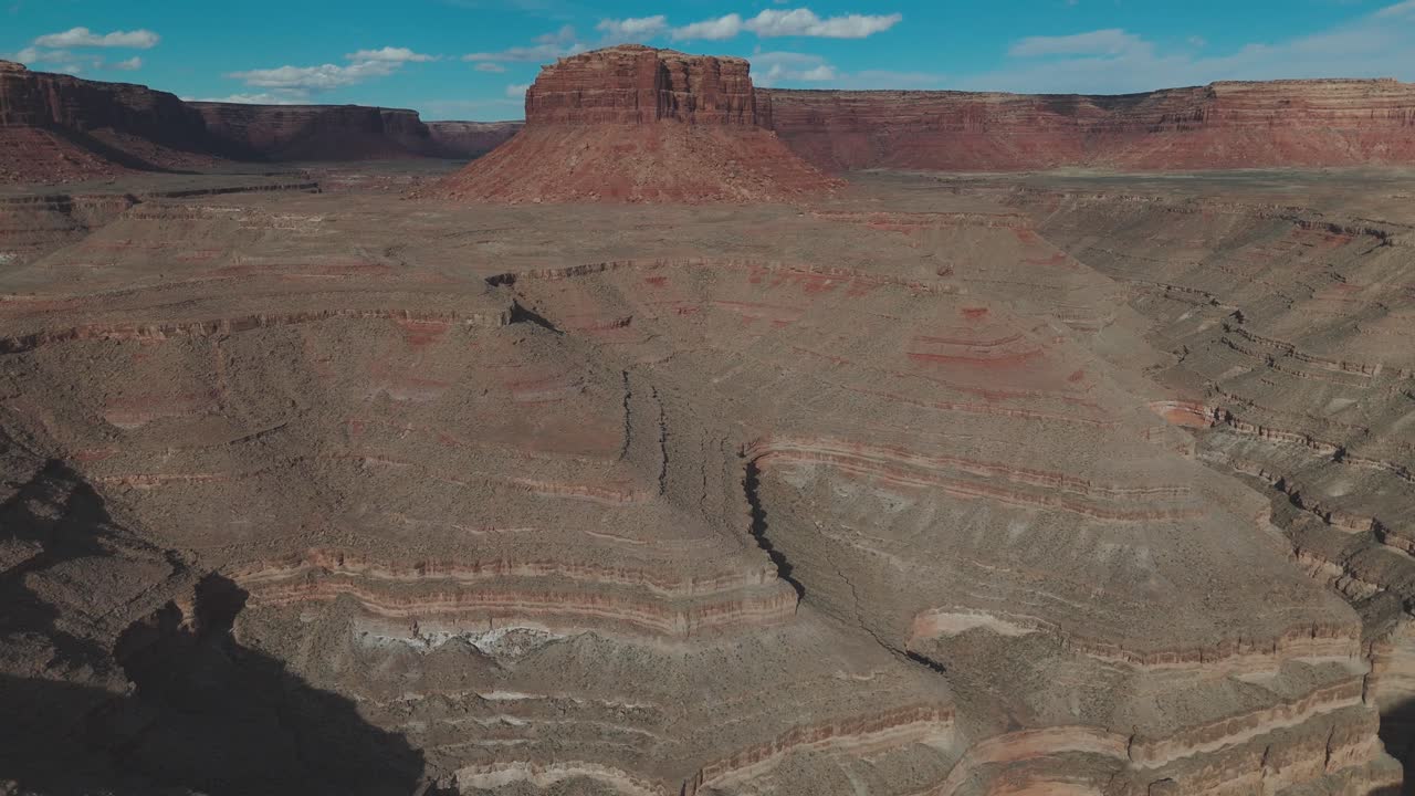 Aerial wide tilt up flying from Gooseneck canyon to red rock spire in Utah