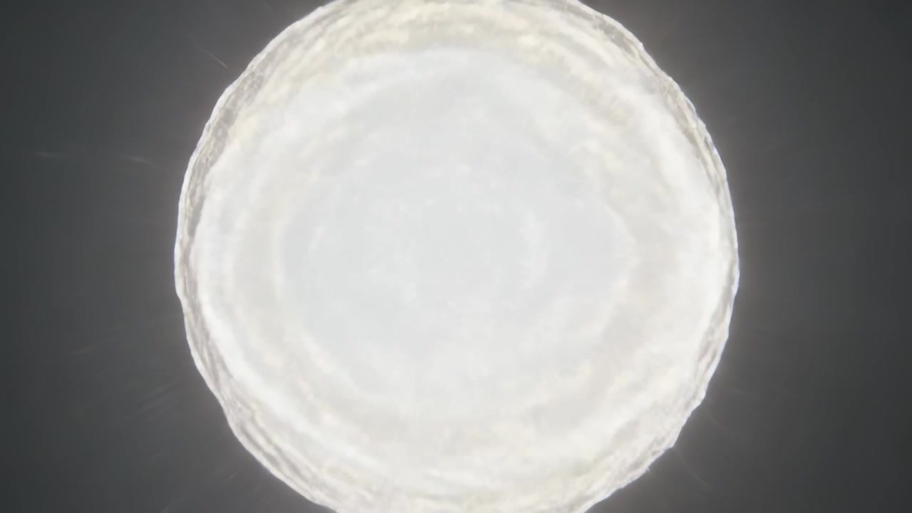 Câmera com zoom focando em luz circular brilhante em teto escuro, revelando halo e superexposição.