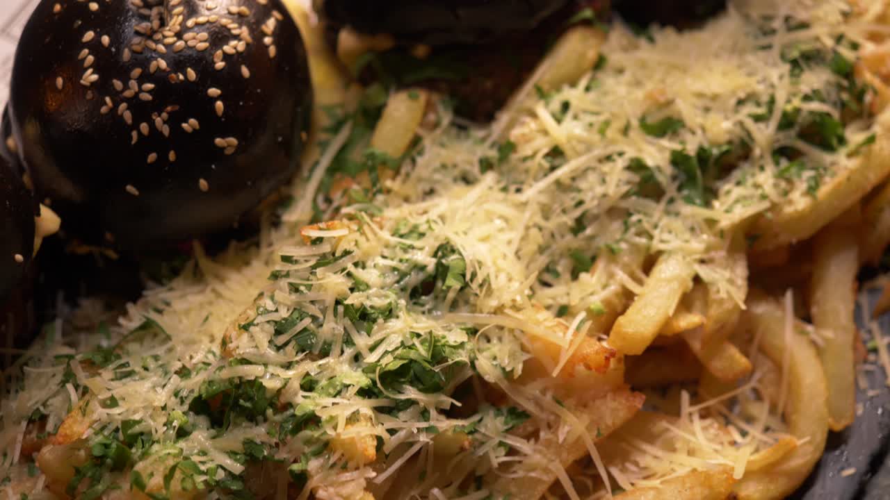 강판 치즈와 신선한 허브로 덮인 감자 튀김을 곁들인 미니 버거