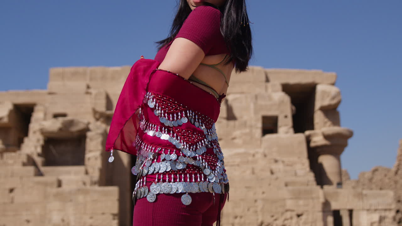 Dancer in traditional attire performing belly dance in front of ancient ruins in Dendera, Egypt