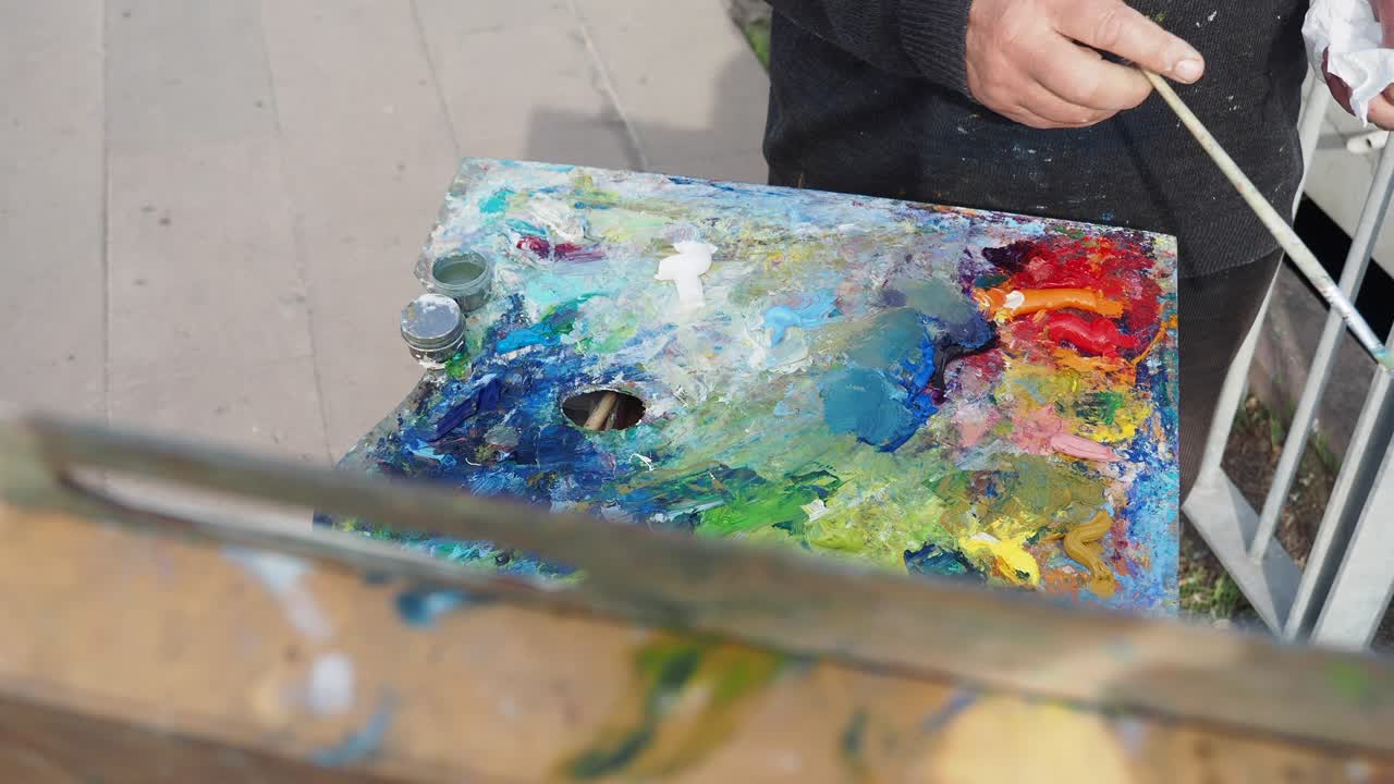 밖에서 팔레트와 질로 그림을 그리는 예술가