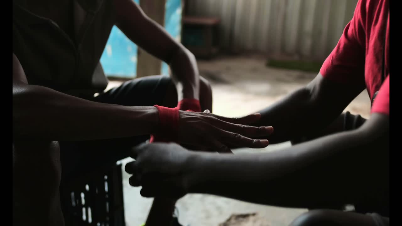 entrenador afroamericano ayudando a un boxeador en el uso de envolturas de manos en el gimnasio 4k