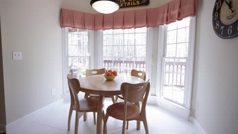 una cocina brillante con grandes ventanas y una mesa de madera en el medio