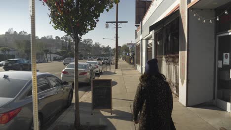 hipster girl walking down sidewalk in urban area, dolly crane shot