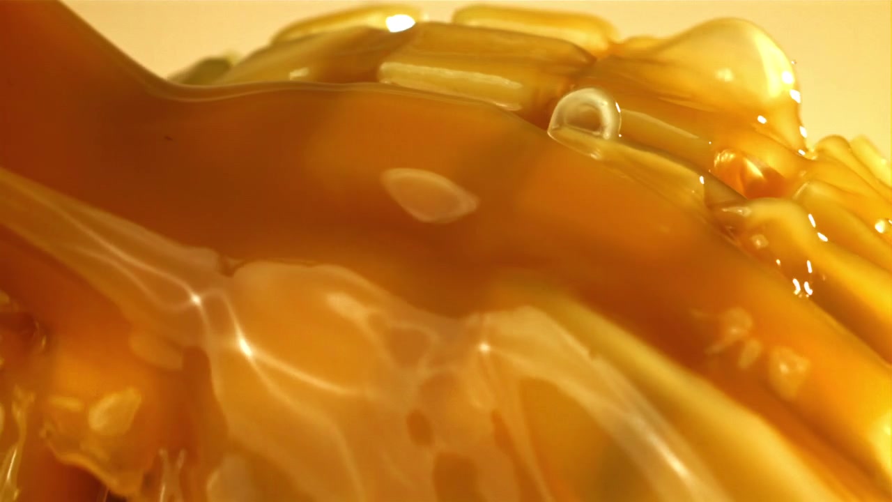 Sirop doré sucré coulant sur des dés de mangue fraîchement coupés.