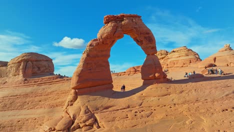 Delicate-Arch-With-Tourists-At-Arches-National-Park,-Utah---aerial-shot