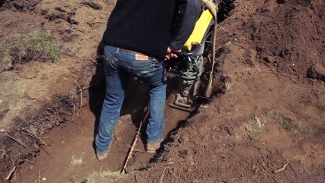 a worker compacts dirt in a trench
