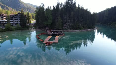 muelle de madera con barcos de remo anclados en el lago verde esmeralda en los dolomitas italianos