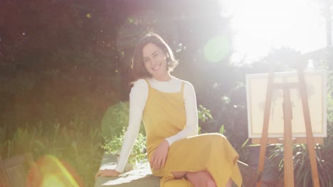 portrait of smiling caucasian woman with brown hair painting in sunny garden