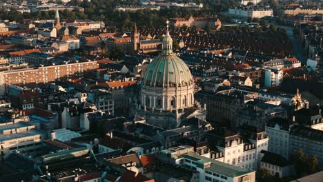 aerial flyover of frederiks kirke church dome at sunrise with warm light in copenhagen