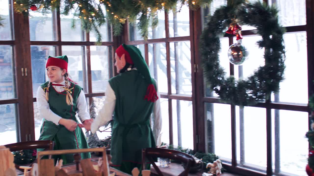 Elves having fun standing by the window in santa claus house with christmas decorations