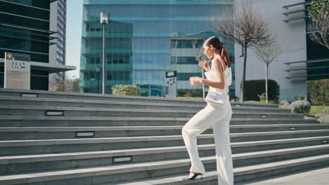 Business lady recording voice message on phone walking upstairs urban park.