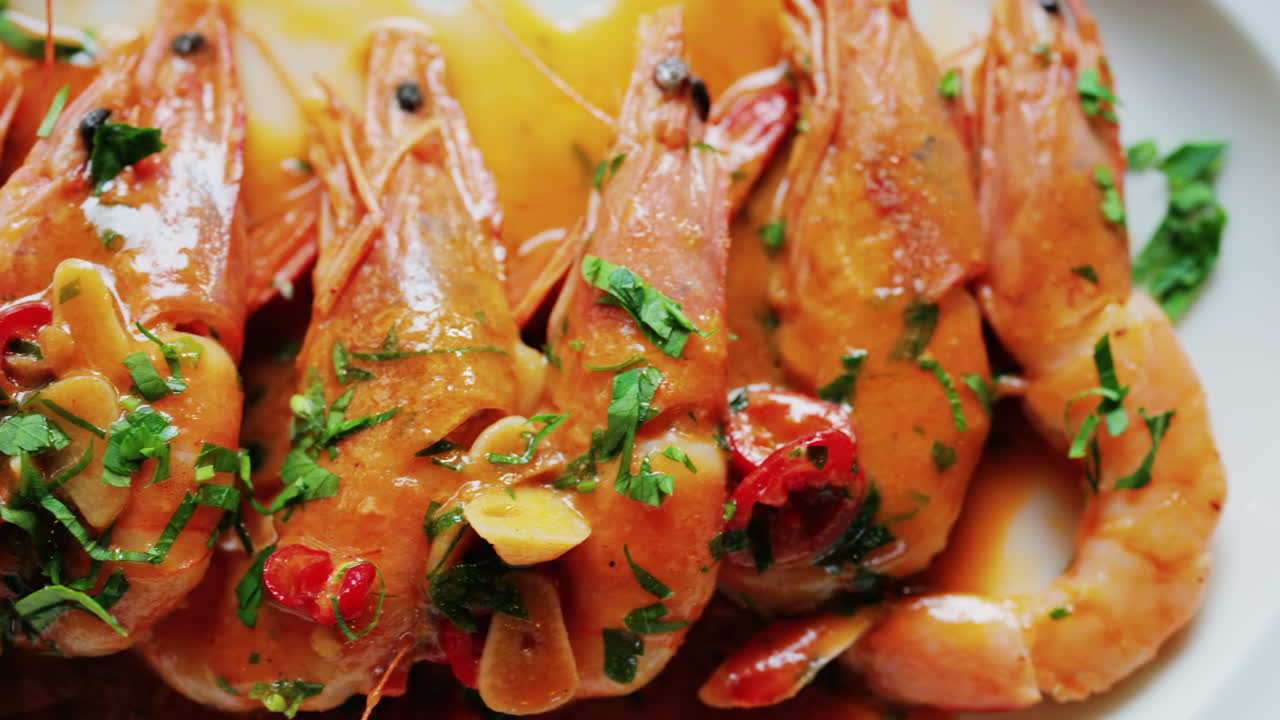 Garlic prawns in a rich sauce topped with herbs on a white plate