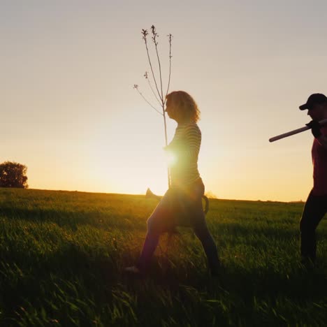 Vista-Lateral-De-Los-Agricultores---Un-Hombre-Y-Una-Mujer-Caminando-Por-El-Campo-Al-Atardecer