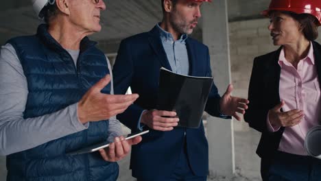 primer plano de un grupo de ingenieros caucásicos e inversores caminando y discutiendo en el sitio de construcción.