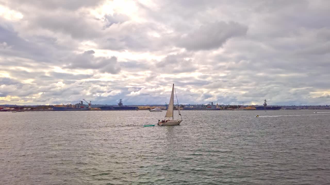 Lonely sail floating on San Diego bay near Coronado bridge at sunset. Cloudy sky. Panoramic shot