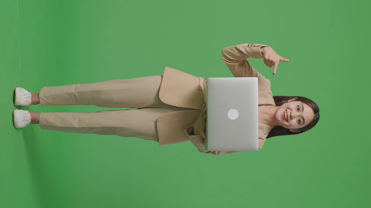 mujer en traje sosteniendo una computadora portátil y señalando