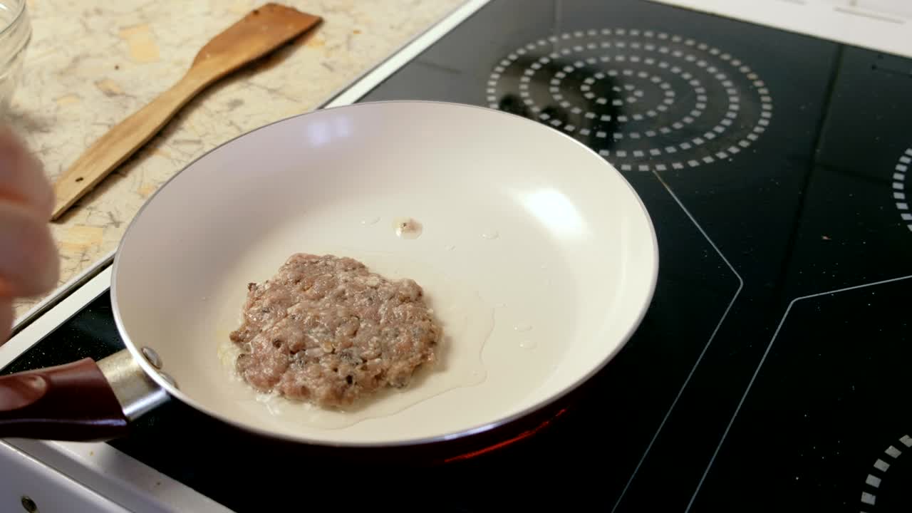 el hombre está asando en la sartén chuletas para hamburguesas.