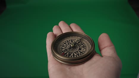 antique compass in hand against green background