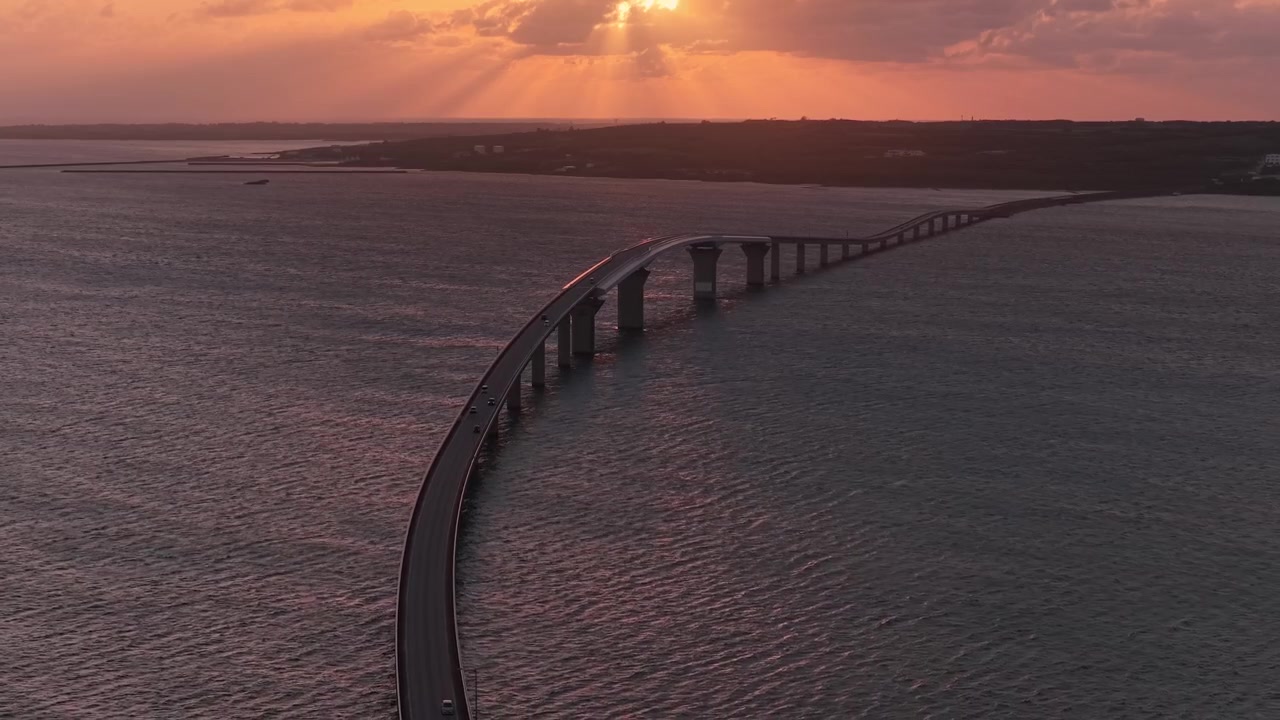 Riprese aeree orizzontali che si muovono lentamente all'indietro sopra il ponte Irabu al tramonto con drammatici raggi di sole su Miyakojima, Okinawa, Giappone.