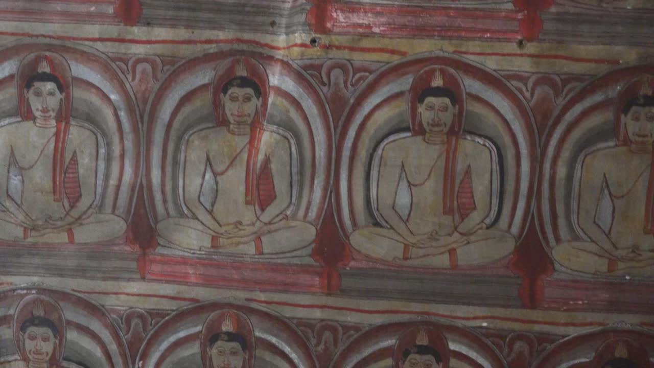 Murales colorati all'interno del Tempio rupestre di Dambulla, Sri Lanka, con mani in meditazione che ripetono un motivo.
