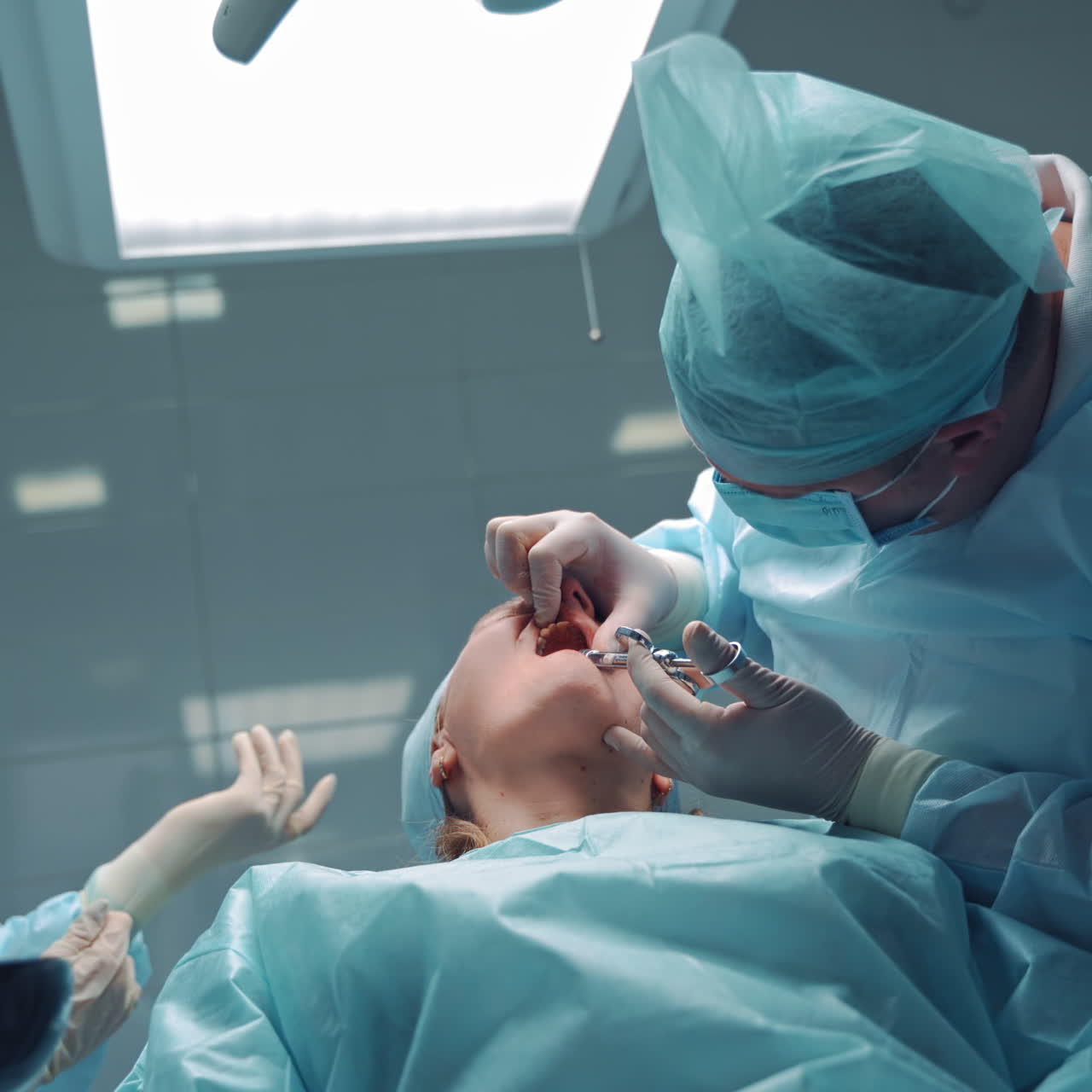 Stomatologist man in special clothes is doing anesthetic injection into the client's mouth. Doctor dentist and his assistant prepare the patient for tooth treatment in dental office.