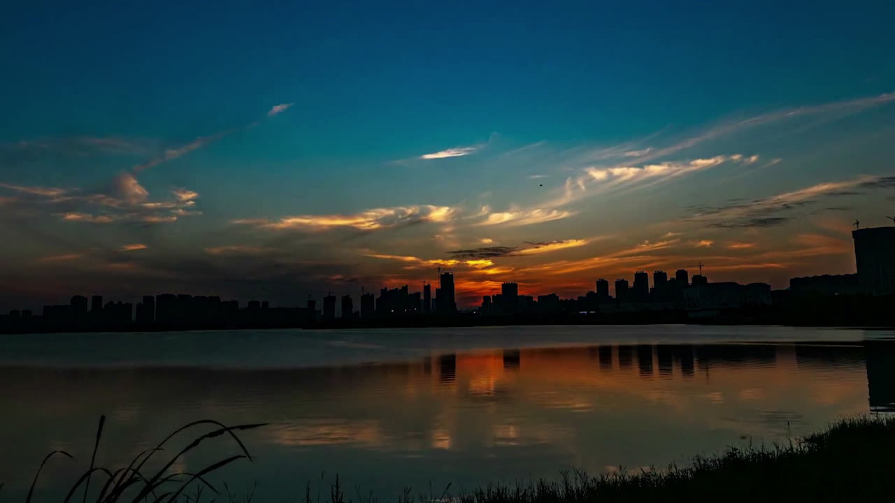 도시 근처의 작은 호수 위에 다채로운 해가 지는 시간 경과 실루, 여름 저녁 비디오