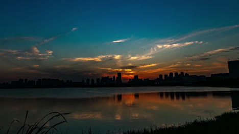 Time-Lapse-Silhouettes-With-Colorful-Sunset-Over-Small-Lake-Near-City,-Summer-Evening-Video