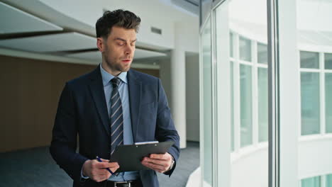 focused businessman reading clipboard walking hallway closeup. serious executive